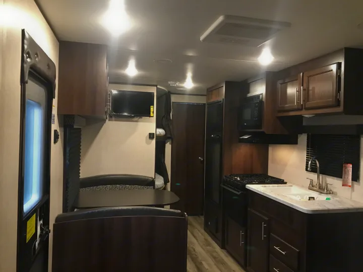 RV rental interior: dining area, full kitchen with stove, microwave, fridge, and bunk beds. AC unit visible.. Jayco Jay Flight SLX 2019