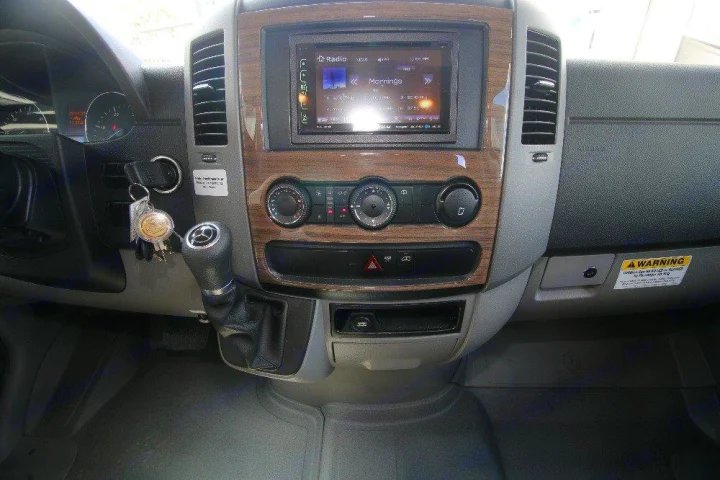Interior of an RV rental's driver area showing a dashboard with infotainment screen, climate controls, gear shift, and keys.. Jayco Melbourne 2019