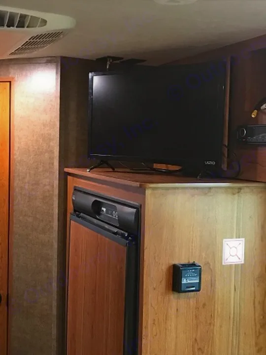 RV rental interior showing a wall-mounted TV, built-in refrigerator, and control panel on wooden cabinetry.. Starcraft Launch 2017