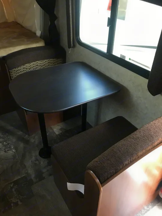 RV rental interior featuring a dark dinette table, bench seating, and a window. A practical and comfortable space for travel.. Jayco Jay Feather 2016