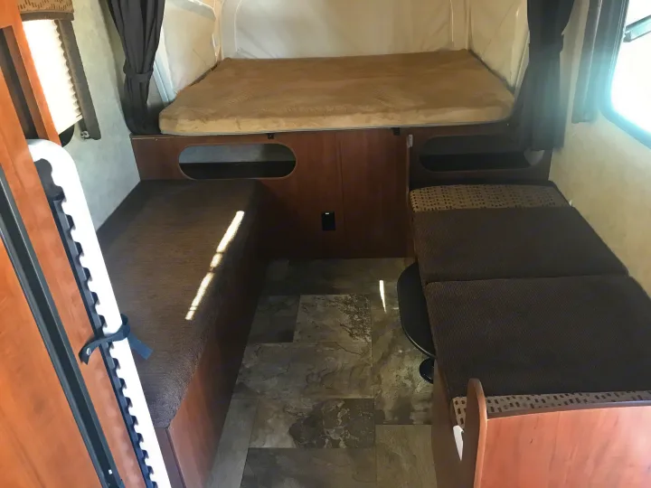 Inside this RV rental: a comfy bed, two bench seats, and a table base on tiled flooring. Compact and functional layout.. Jayco Jay Feather 2016