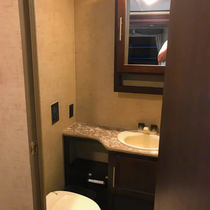 Clean RV rental bathroom with sink, mirror, toilet, and vanity. Perfect for travel convenience.. Forest River Surveyor 2015