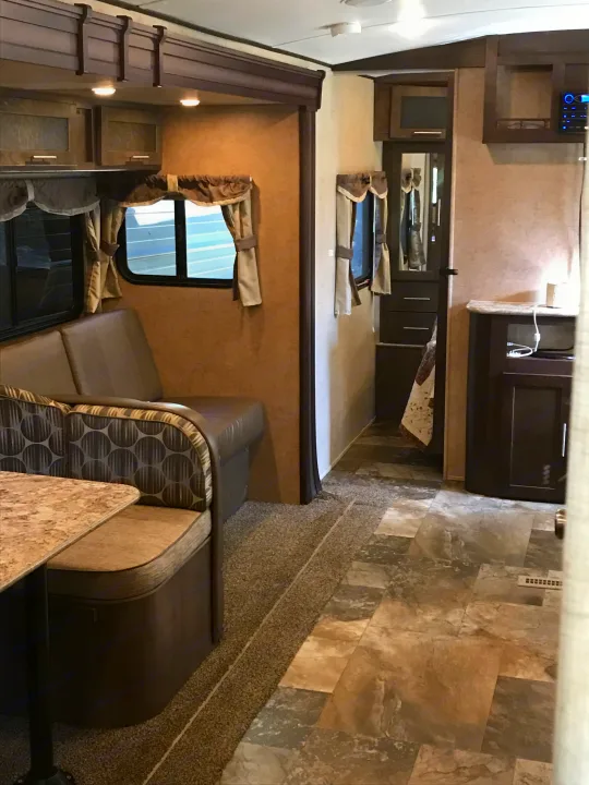 RV rental interior showcasing a cozy dinette, overhead cabinets, and a hallway with entertainment system.. Forest River Surveyor 2015