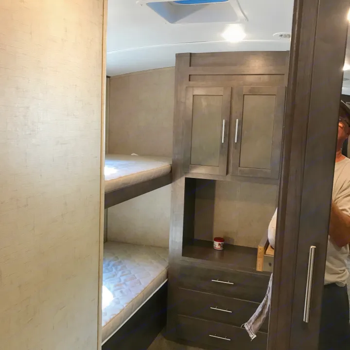 Spacious RV rental interior with comfortable bunk beds and ample built-in storage for your travel essentials.. Forest River Surveyor 2015