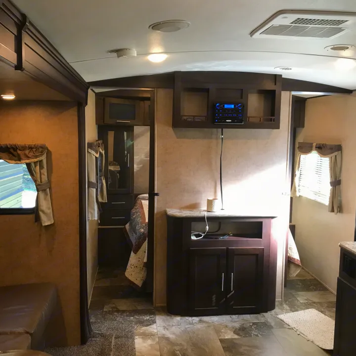 Explore this modern RV rental interior featuring a cozy living area, compact bedroom, and entertainment setup. Ideal for travel!. Forest River Surveyor 2015