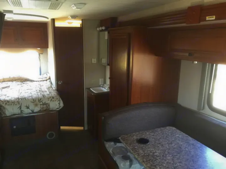 Explore this RV rental's interior: a compact living space featuring a comfy bed, dinette, and sink. Ready for adventure!. Fleetwood Tioga Ranger 25G 2011