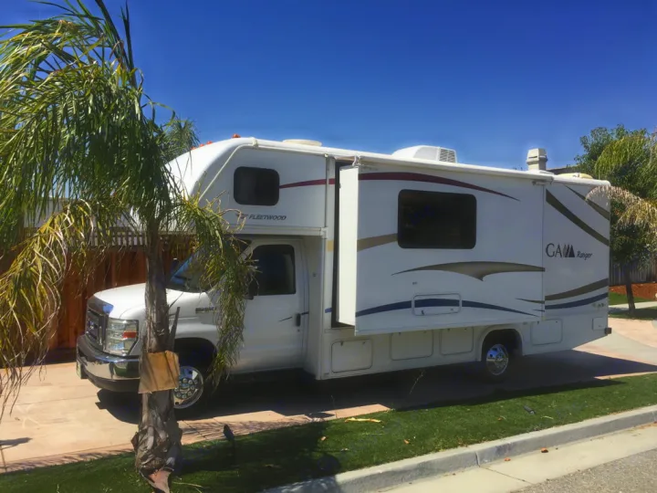 Bright white Fleetwood motorhome RV rental with extended slide, parked on a sunny driveway.. Fleetwood Tioga Ranger 25G 2011