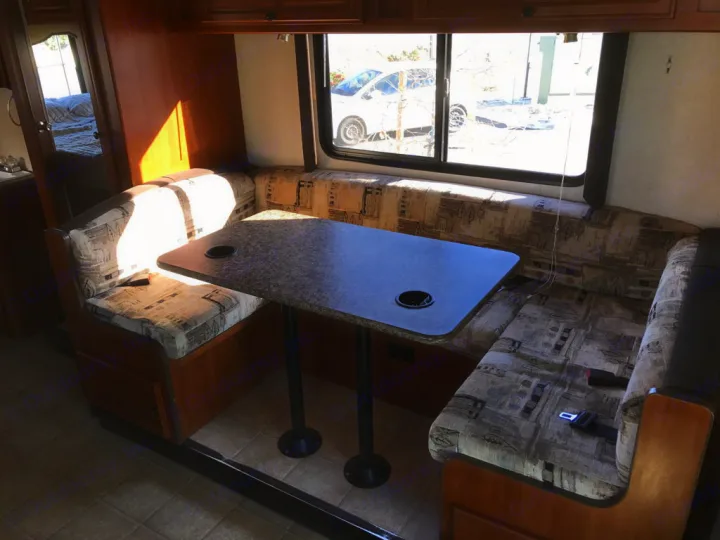 RV rental dinette interior with patterned cushions, table, and window view. Seatbelts visible.. Fleetwood Tioga Ranger 25G 2011
