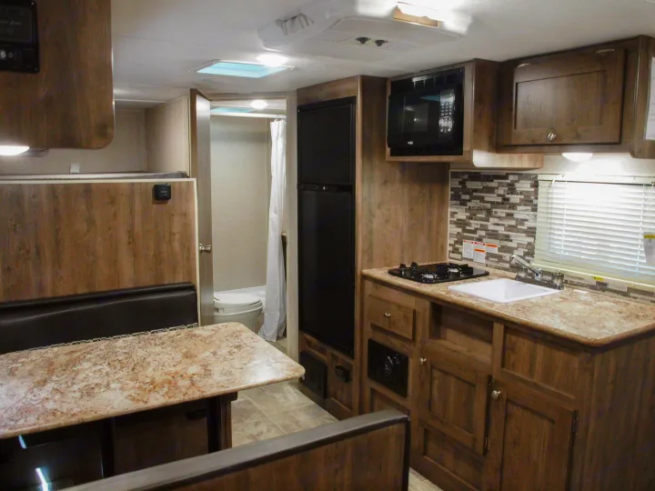 RV rental: Interior shows light wood kitchen (stove, sink, microwave), dinette, and bathroom in compact layout.. Dutchmen Aspen Trail LE 1950BH 2020