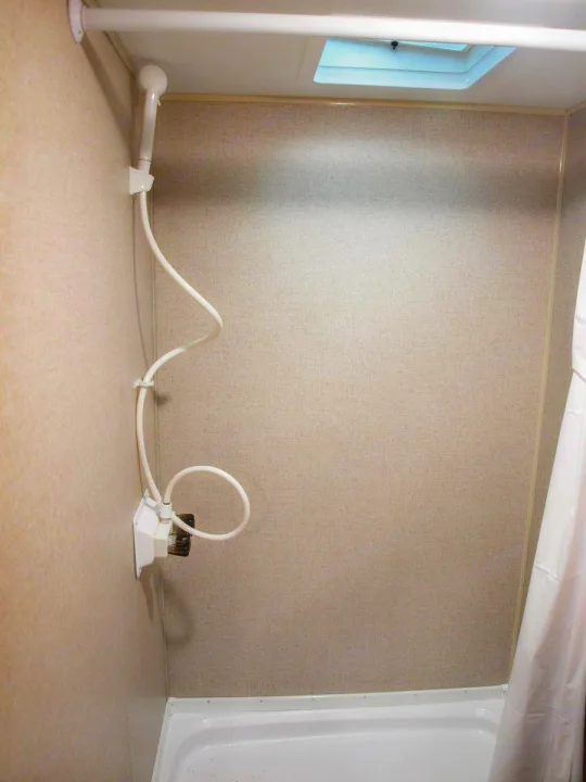 Compact shower in an RV rental, featuring a handheld showerhead and skylight for practical use on the go.. Dutchmen Aspen Trail LE 1950BH 2020