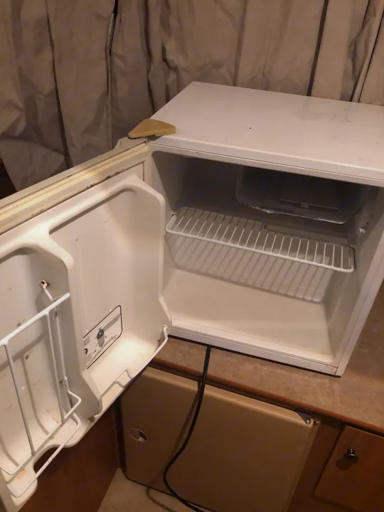 This RV rental features an open, white mini-fridge with empty shelves and a small freezer, ready for use.. Starcraft St 2006