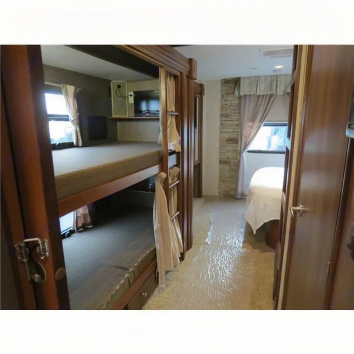 RV rental interior featuring cozy bunk beds and a private bedroom, with protective plastic covering the floor.. Forest-River Georgetown 2014