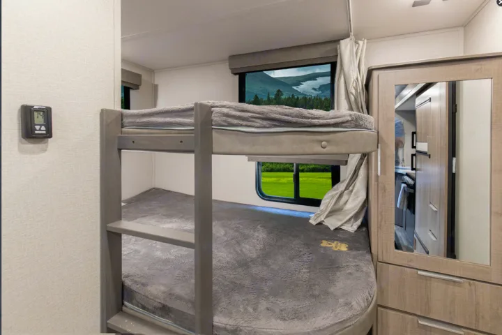 Cozy RV rental interior with bunk beds, scenic window views, and a mirrored wardrobe reflecting the kitchen area.. Grand Design Imagine XLS 19BWE 2020