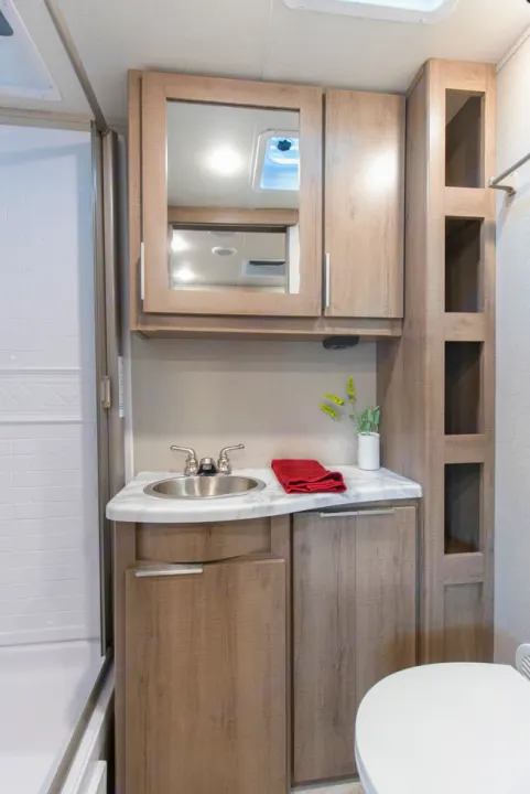 This RV rental's bright bathroom features a shower, vanity sink, mirrored cabinet, and built-in shelving. Ready for your trip!. Grand Design Imagine XLS 19BWE 2020