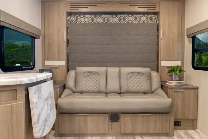 This modern RV rental interior features a comfy sleeper sofa, hidden wall bed, and efficient storage solutions for a cozy adventure.. Grand Design Imagine XLS 19BWE 2020