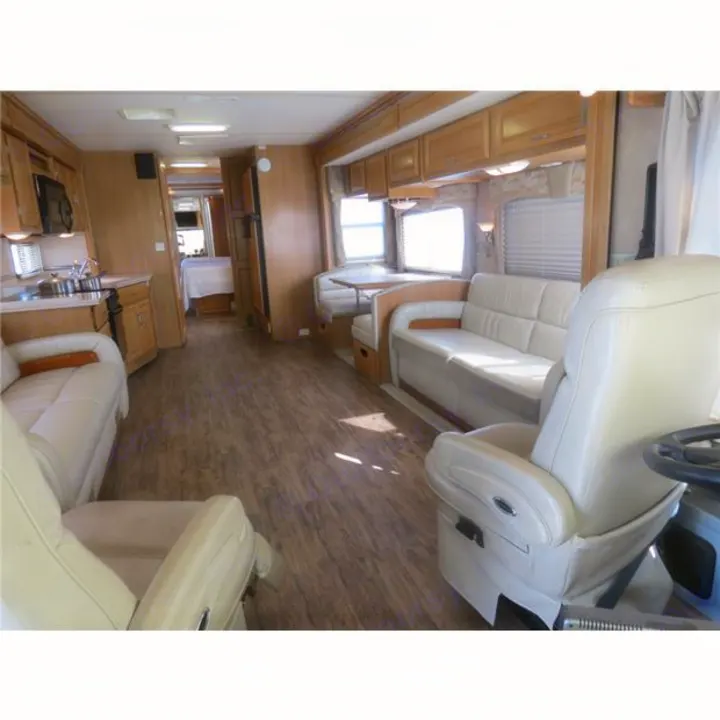 Bright RV rental interior: well-appointed kitchen, cozy dinette, comfortable seating, wood-look floor & rear bedroom.. Fleetwood Discovery 2006