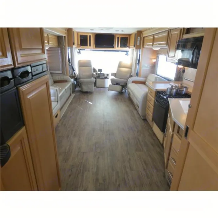 Spacious RV rental interior showcasing a kitchen, living area with sofas, and front captain's chairs; a comfortable motorhome setup.. Fleetwood Discovery 2006