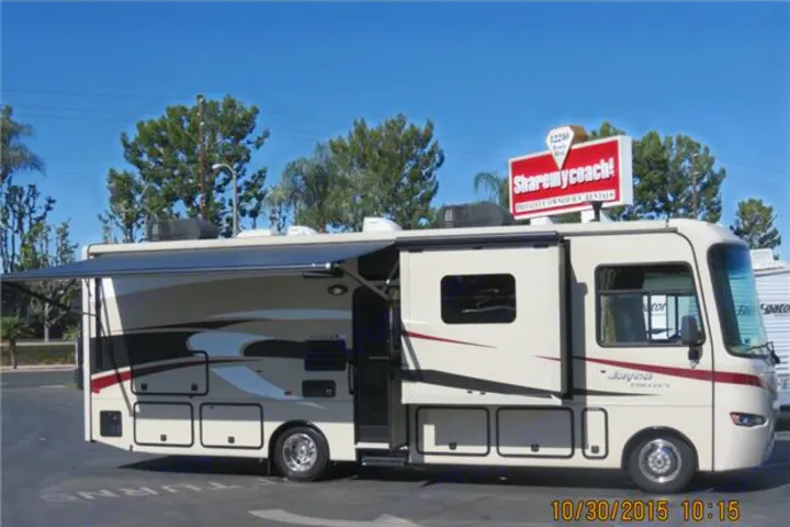Beige Jayco Greyhawk motorhome with awning extended, advertised for RV rental.. Jayco Precept 2014
