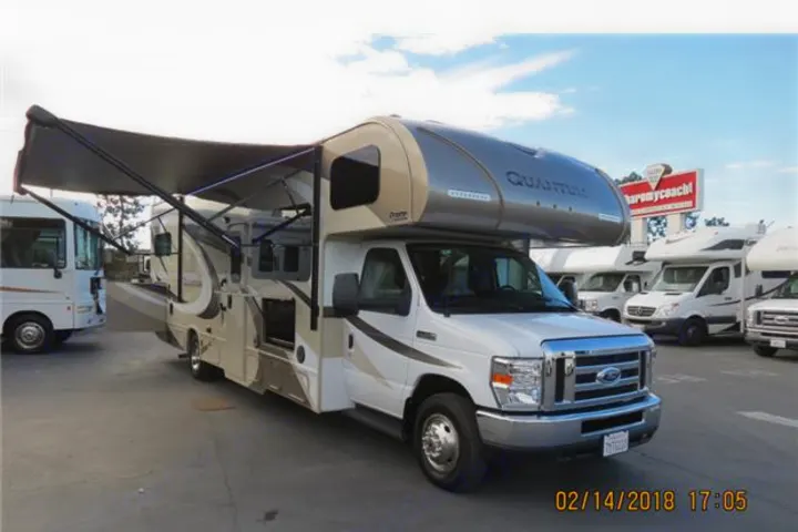White and tan Class C Quantum RV motorhome with an extended awning, likely for rv rental at a dealership.. Thor Quantum 2017