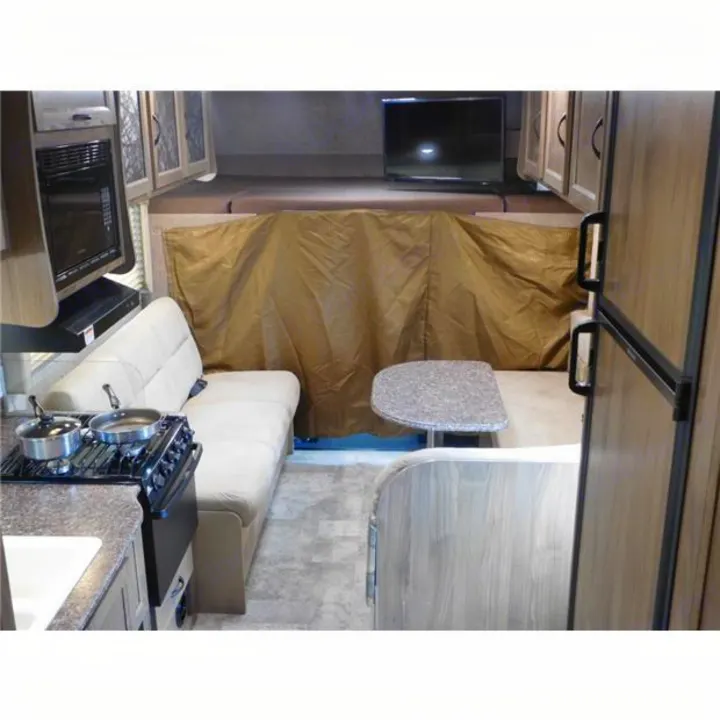 RV rental interior: A practical layout with kitchen, dinette, refrigerator, and overhead sleeping area.. Coachmen Freelander 2017