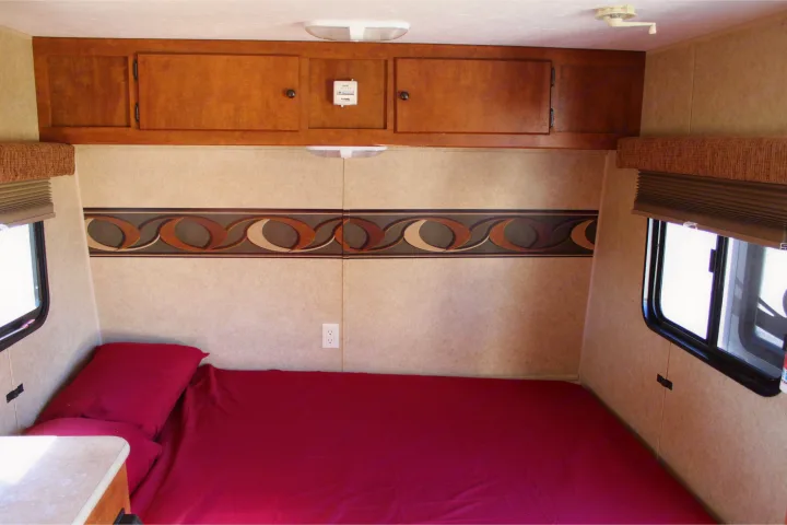 RV rental interior: Compact bedroom with red bedding, wooden cabinets, and windows on both sides.. Skyline Aljo 2012