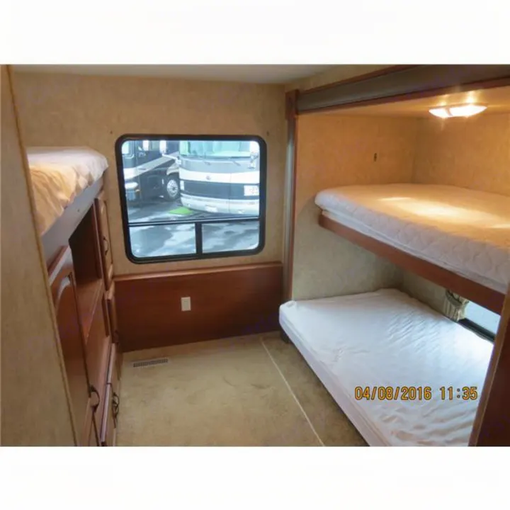 RV rental interior: bunkhouse with four beds, a window showing other RVs, and built-in storage.. Forest-River Surveyor 2011