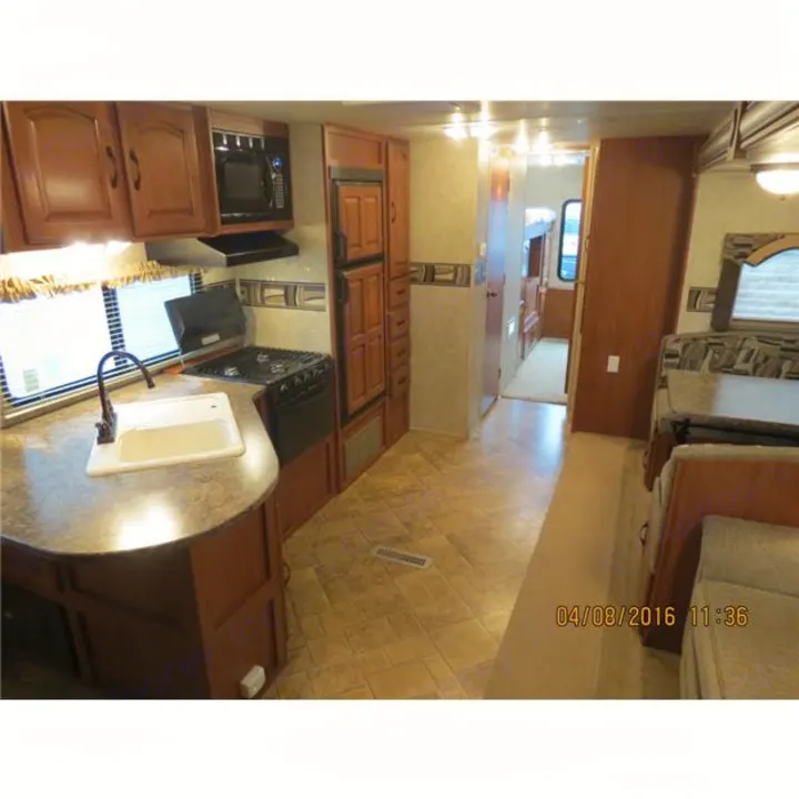 Inside an RV rental: a well-equipped kitchen, central living area, and hallway leading to private bunk beds. Perfect for trips.. Forest-River Surveyor 2011