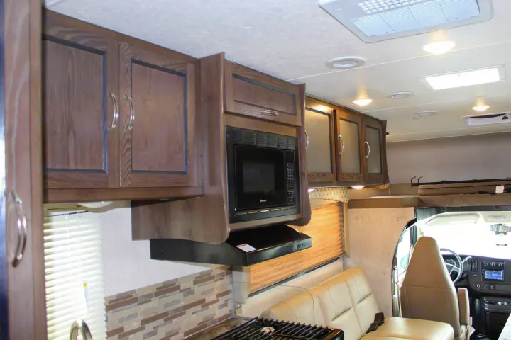 RV rental interior: kitchen with microwave, dining seating, overhead bunk, and driver's cabin views.. Coachmen Freelander 2020