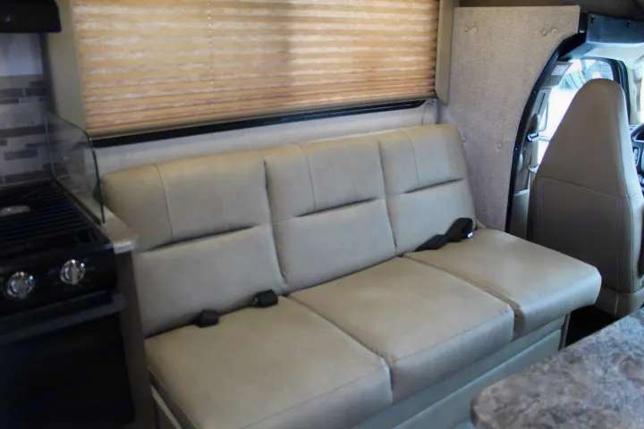 RV rental living space: sofa with seatbelts, kitchen cooktop, and front cabin view for easy travel.. Coachmen Freelander 2020