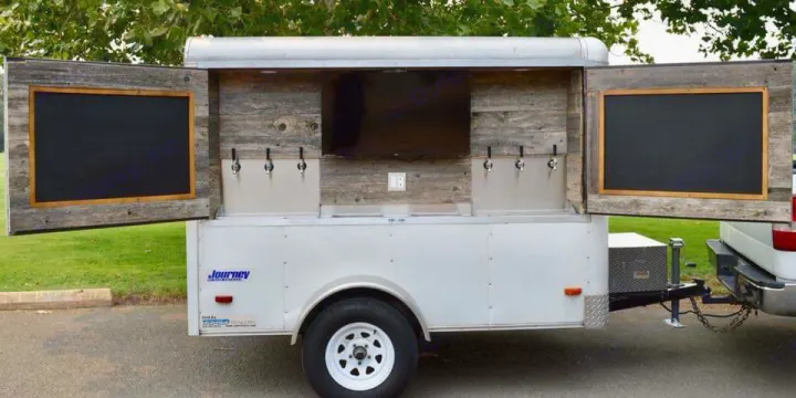 Mobile bar trailer with taps, TV, and chalkboards, perfect for events. Ideal addition to any RV rental adventure.. GameDay Beverage Trailer 2019