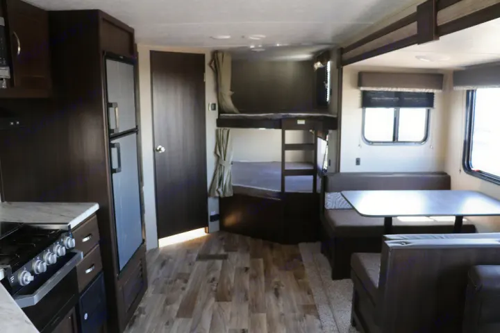 Spacious rv rental interior featuring a full kitchen, bunk beds, and a dining area with dinette. Perfect for family adventures.. Keystone Springdale 2020