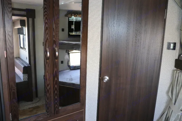 Spacious RV rental interior with dark wood-look doors, featuring bunk beds reflected in a mirror and a dinette.. Keystone Springdale 2020