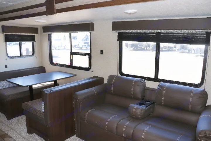 View inside an RV rental's living area: brown dinette, sofa with cupholders, and large windows.. Keystone Springdale 2020