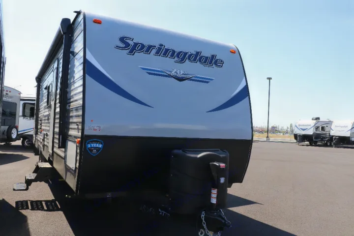 Front view of a Springdale RV travel trailer, ideal for RV rental. This grey and black recreational vehicle is in a sunny lot.. Keystone Springdale 2020