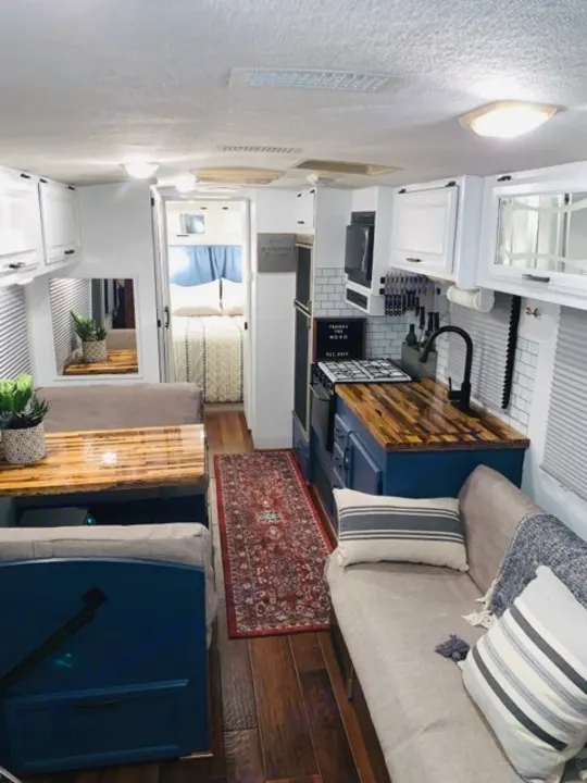 Spacious & bright RV rental interior featuring a modern kitchen, dining area, and bedroom.. Fleetwood Flair 1997