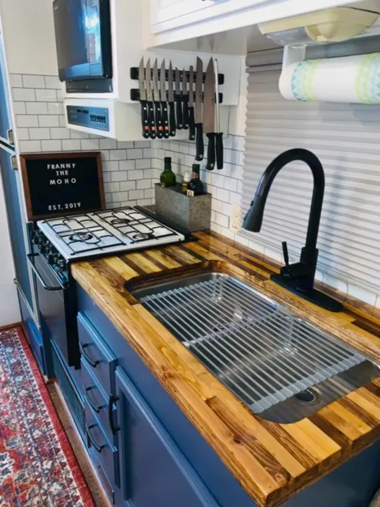 Inside a stylish RV rental kitchen: butcher block counters, blue cabinets, full sink & stove.. Fleetwood Flair 1997