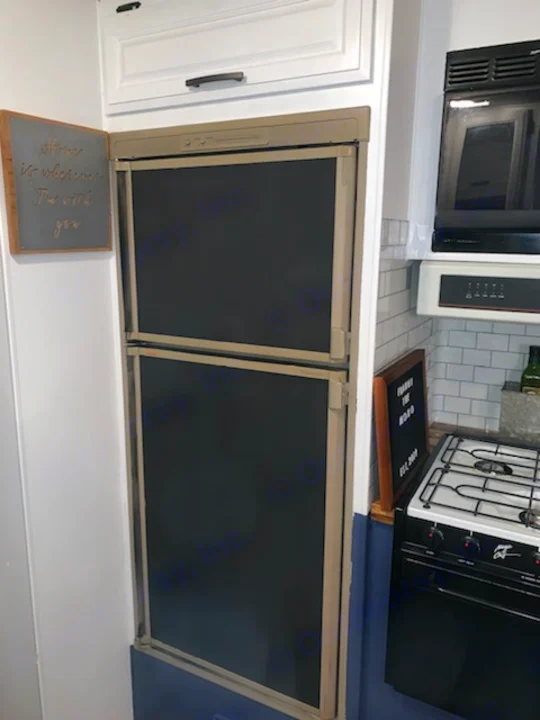 This RV rental kitchen features a compact refrigerator, stove, microwave, and decor, perfect for cozy travels.. Fleetwood Flair 1997