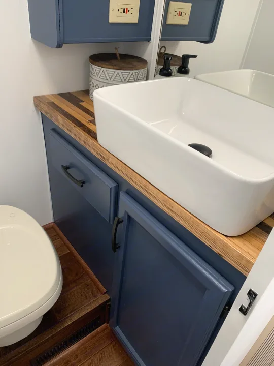 RV rental bathroom: compact blue vanity with wood counter, white vessel sink, and toilet.. Fleetwood Flair 1997