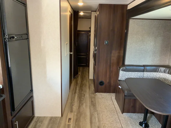 RV rental interior: A modern dinette, refrigerator, and hallway leading to other rooms, featuring dark wood accents and light walls.. Jayco Jay Flight 2019