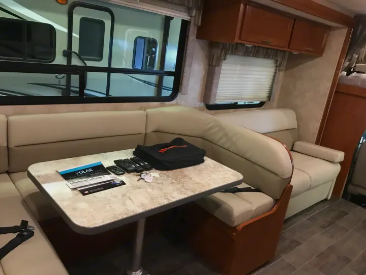 Step inside this RV rental's cozy dining area: comfortable bench seating, a table with remotes & keys, and large windows.. Winnebago Minnie Winnie 2019