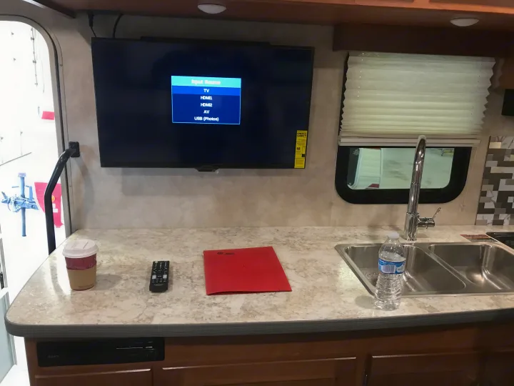 RV rental interior, showcasing the TV input menu, kitchen counter with sink, and coffee.. Winnebago Minnie Winnie 2019