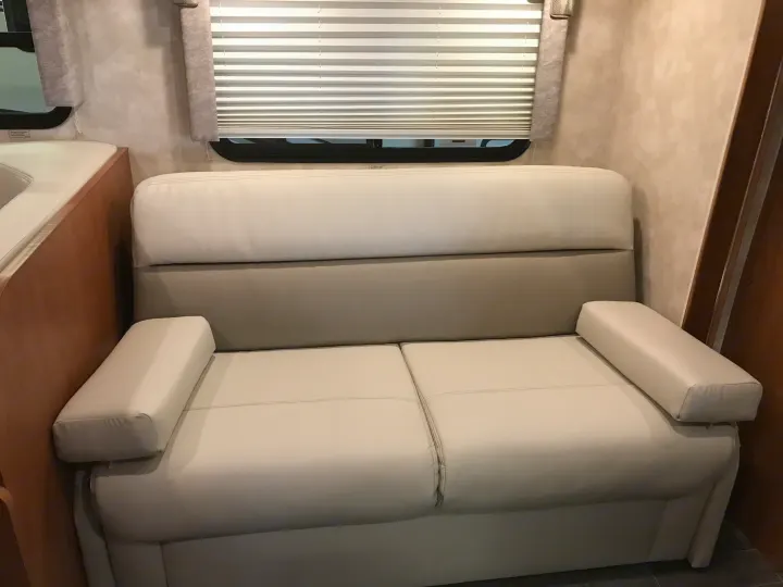 RV rental interior featuring a light grey sofa with cream cushions and window blinds.. Winnebago Minnie Winnie 2019