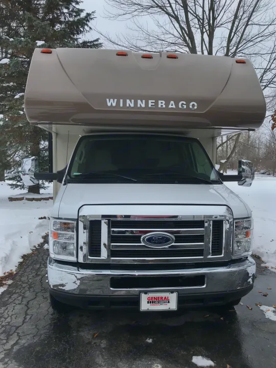Front view of a white and tan Winnebago RV on a Ford chassis, parked in a snowy driveway. Perfect for your next rv rental adventure!. Winnebago Minnie Winnie 2019