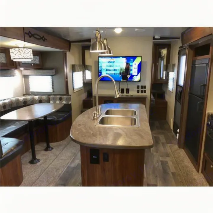 Spacious RV rental interior featuring a kitchen island with sink, booth dining, and TV, ideal for travel.. Heartland Wilderness 2018