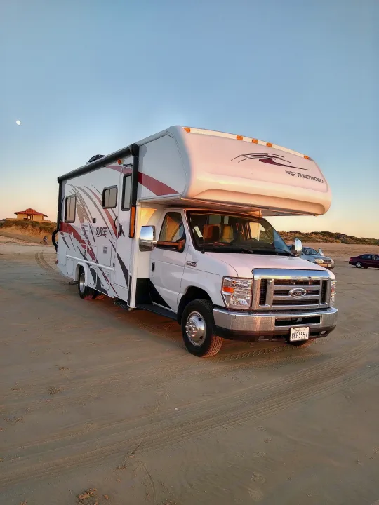 White RV rental on a sandy beach under a clear sky with the moon. Ideal for a serene outdoor adventure.. Fleetwood Other 2018