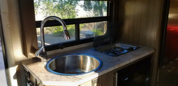 RV rental kitchen features: stainless steel sink, two-burner cooktop, and a window looking outdoors.. Thor Motor Coach Gemini 2016