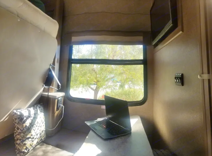 Bright RV rental interior. Laptop on table by window with tree view. Perfect travel workspace.. Thor Motor Coach Gemini 2016