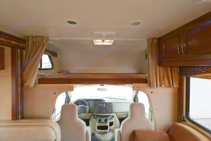 Inside this RV rental: view of the front driving area, overhead bunk bed, and comfortable main cabin seating.. Thor Motor Coach Freedom Elite 2013