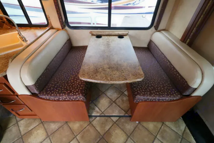 Enjoy meals in this cozy RV rental dinette featuring booth seating, a spacious table, and nearby kitchen counter.. Thor Motor Coach Freedom Elite 2013