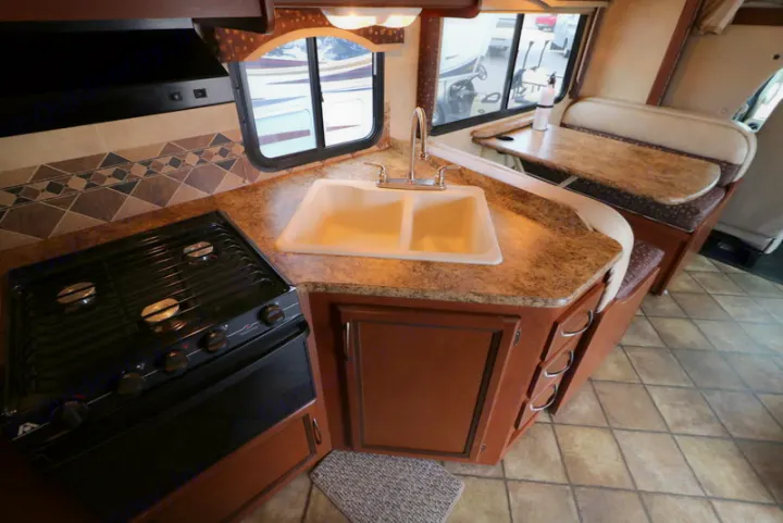 This RV rental offers a well-equipped kitchen with a stove, double sink, and a cozy dinette for meals on the road.. Thor Motor Coach Freedom Elite 2013